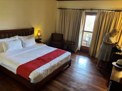 A hotel room featuring a bed, nightstand, and a woman.