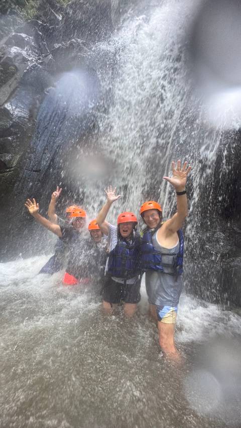 People enjoying a waterfall adventure with safety gear.