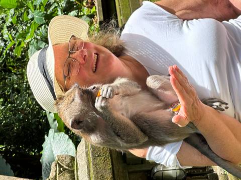 Woman smiling with a monkey on her shoulder.