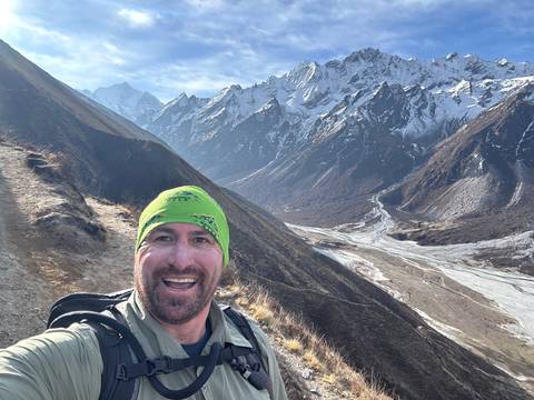 Man in a beanie with snowcapped mountains in the background.