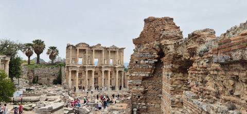 Archaeological ruins with a large structure in the background.