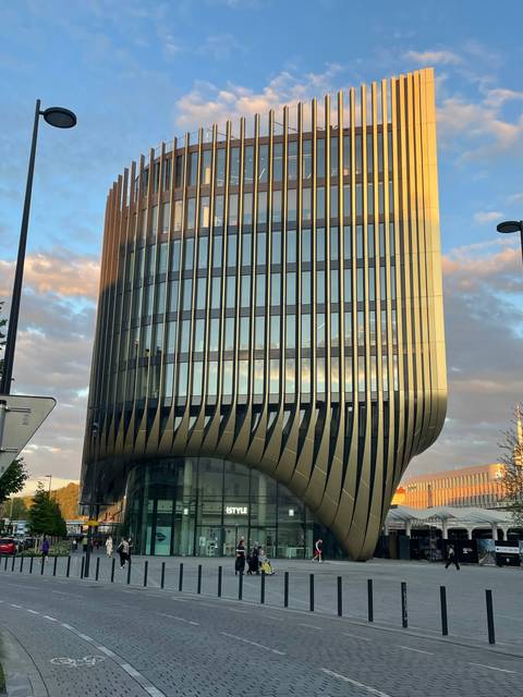 Modern building with reflective glass and vertical metallic lines.