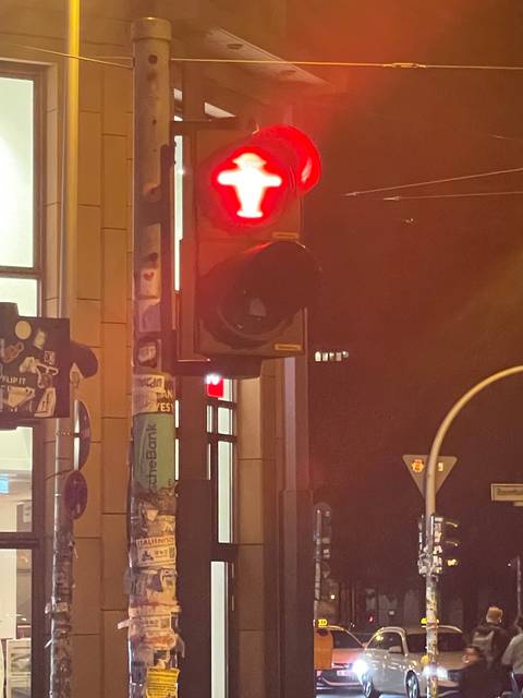 Traffic light showing red at night with street background.