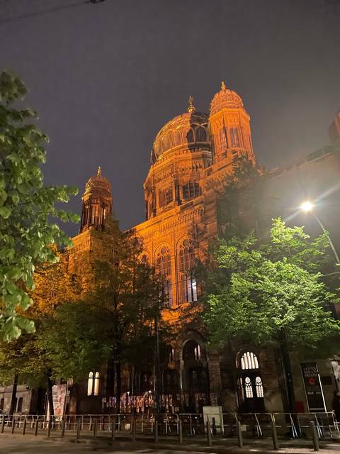 Illuminated historic building at night surrounded by trees.