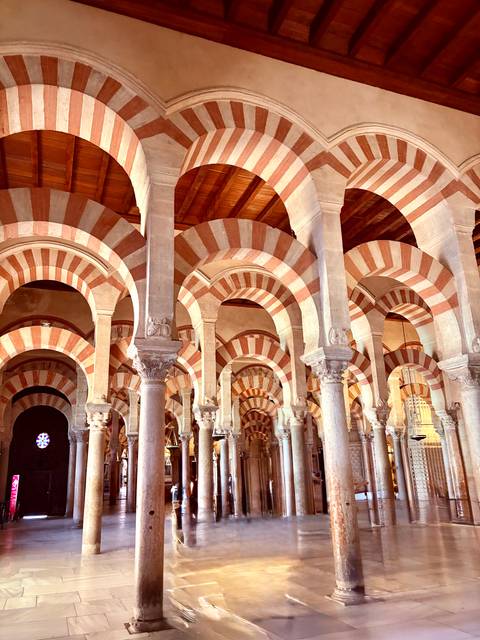       Arched interior of a historic mosque with striped patterns.
  