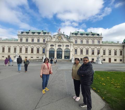 A group of people outside a grand historic palace.