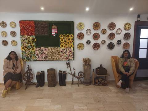 Two women seated in a cultural crafts display room.