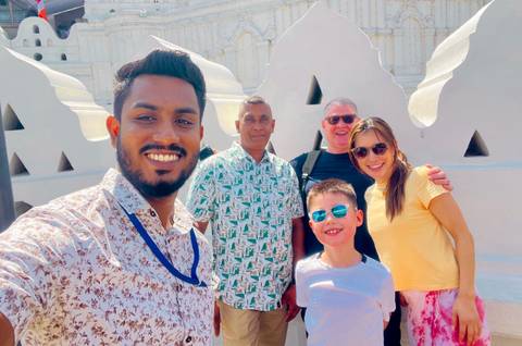       A group of people taking a selfie in front of a geometric white wall.
  