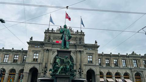       Historic building facade with flags in Zurich.
  