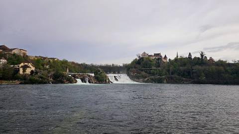       A large waterfall with buildings in the background.
  