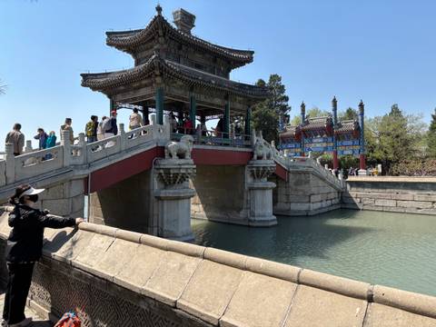 People crossing a traditional stone bridge over a river.