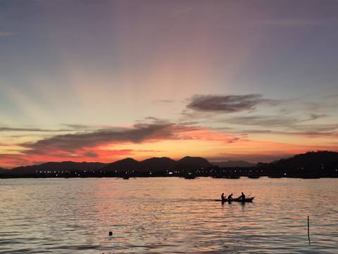 Silhouette of a boat against a vibrant sunset on the water.