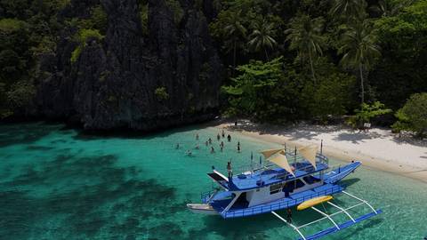       Boat anchored near a scenic beach with clear blue water.
  