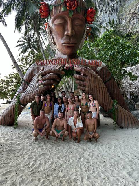       Large group of people posing under a decorative arch.
  