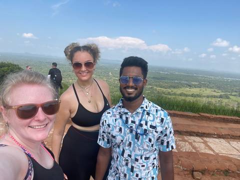 Three people on a viewpoint with a scenic background.