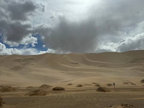       Sand dunes under a partly cloudy sky.
  