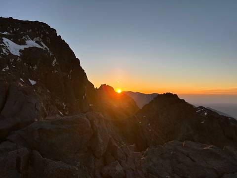 Sun setting behind a mountain ridge.
