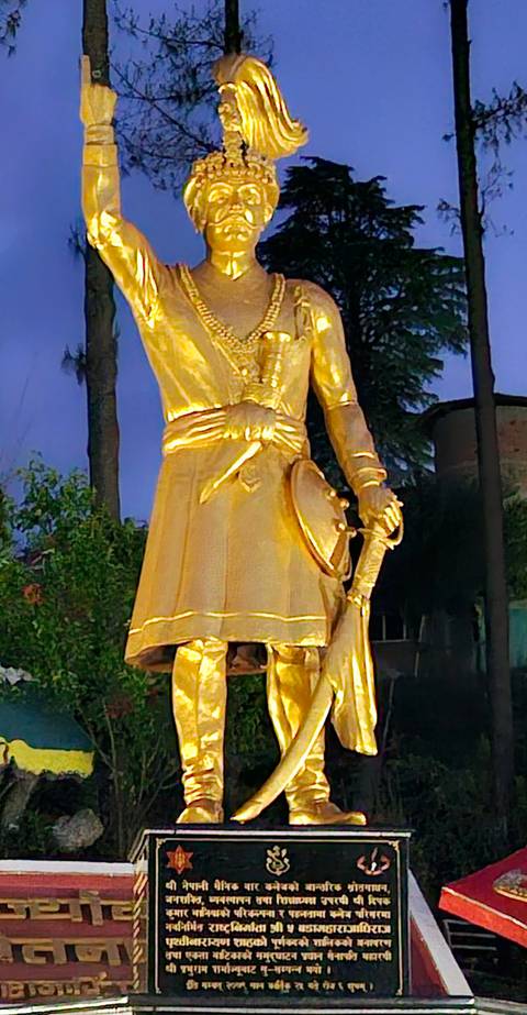 Statue of a golden figure holding a shield at dusk.