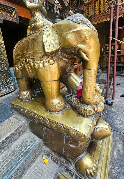 Brass elephant statue detail with a base showing a small snake.