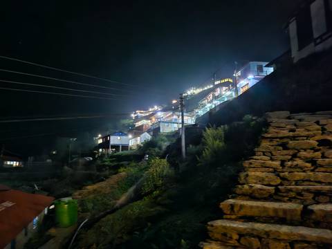       Buildings on a hillside lit up at night.
  