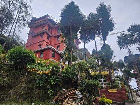       Red building surrounded by trees and plants.
  