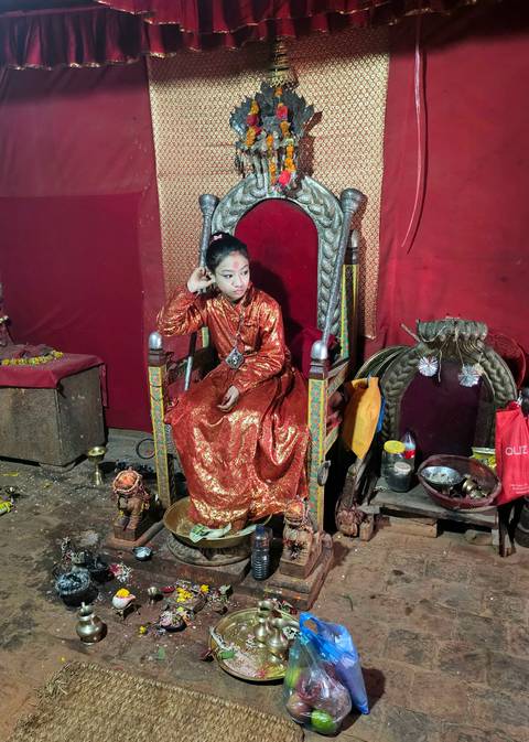       Girl dressed in traditional attire sitting on a chair.
  