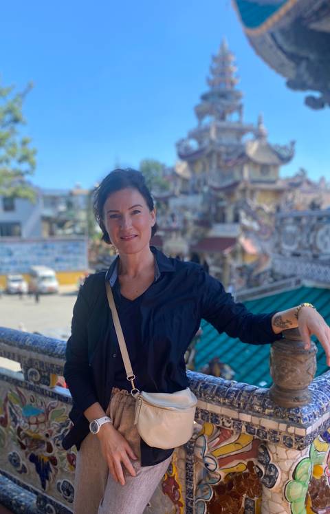       Smiling woman posing in front of a temple.
  