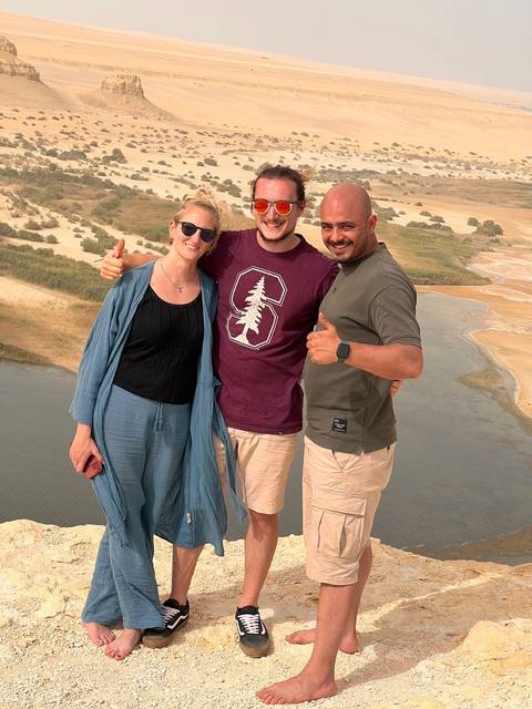       Three people posing with a scenic landscape in the background.
  