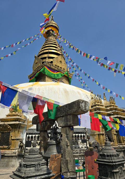       Colorful flags fluttering around a large golden stupa.
  
