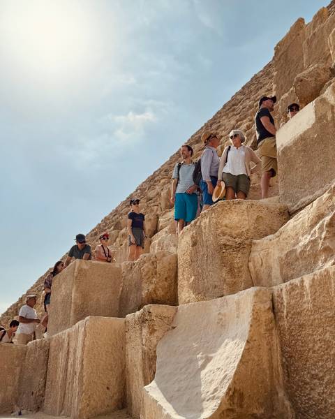       Tourists climbing a pyramid.
  