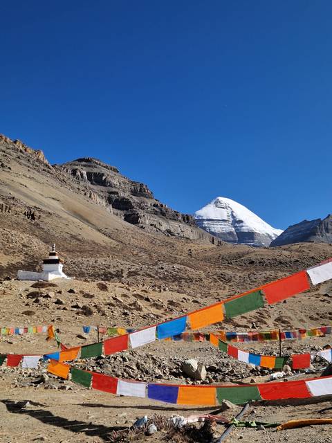 Mountain landscape with white peaks and fluttering prayer flags.