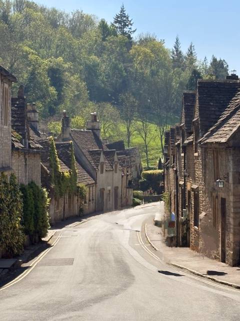 Quaint village street with stone houses and greenery.
