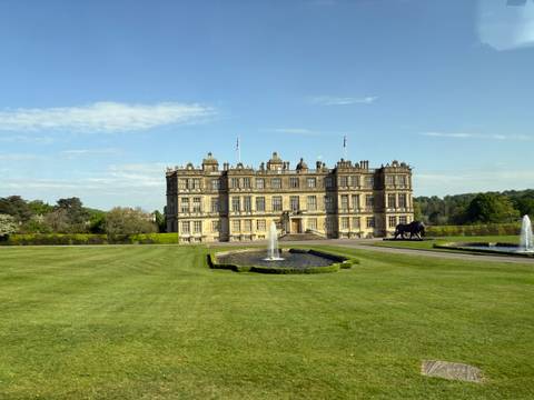 Large historic manor house surrounded by well-maintained gardens.