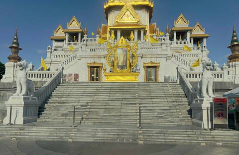       Golden Buddhist temple with statues and flags.
  