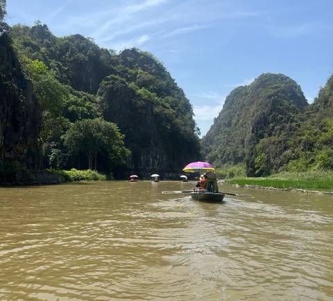       Rowing boats on a scenic river through limestone karsts.
  