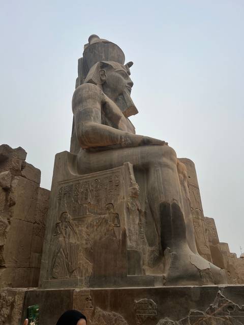       Ancient statue seated with hieroglyphs.
  