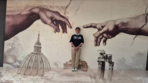Individual stands before a mural featuring iconic Italian landmarks.