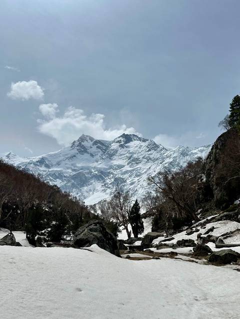 Snow-covered mountain range under a cloudy sky.