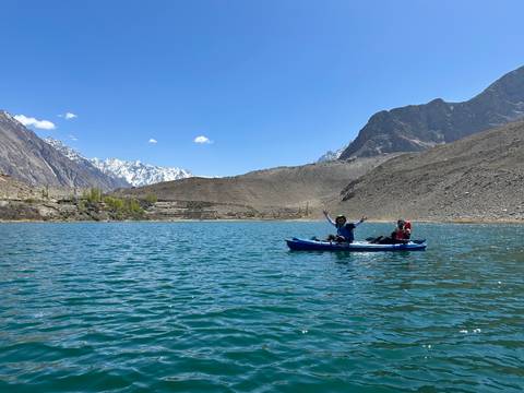 Kayakers on a mountain lake, with snow-capped peaks in the background.