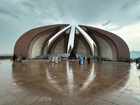 Monument with large, petal-like structures and visitors walking around.