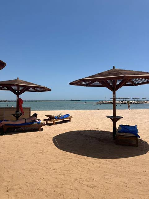 Beach setup with sunbeds and umbrellas facing the sea.