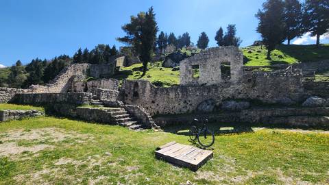       Ruins of an ancient stone structure in a grassy landscape with a bicycle.
  