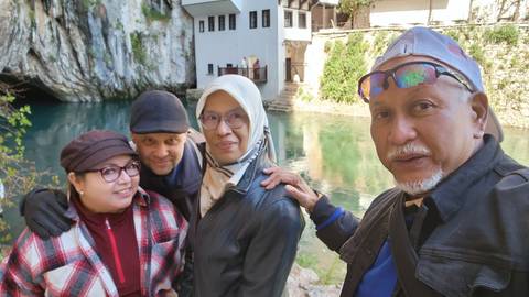       Group of people posing near a scenic river and rock formations.
  