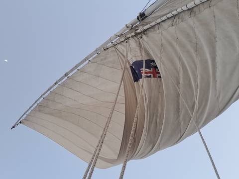 A sailboat with an Australian flag on a clear sky day.