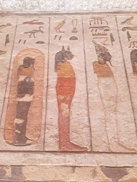 Ancient wall carvings depicting figures with colored robes.