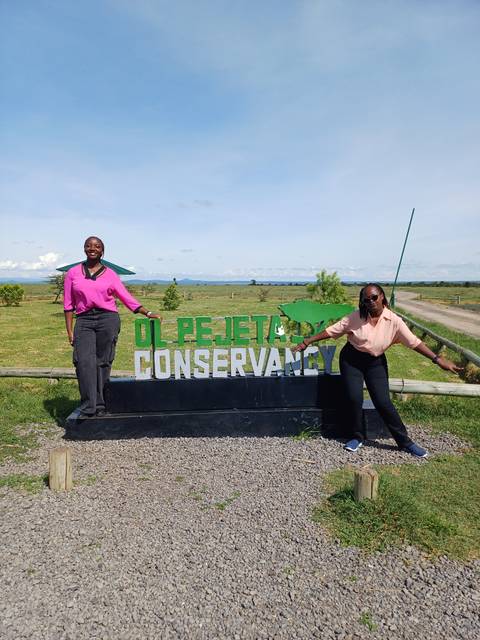People posing by the Ol Pejeta Conservancy sign.