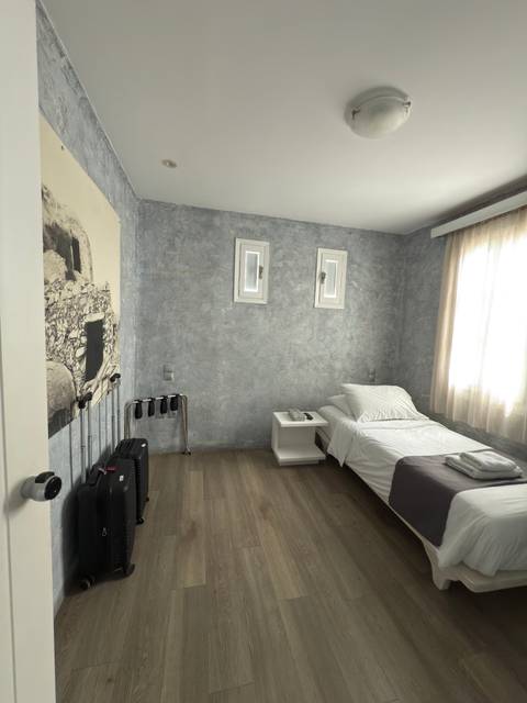 Minimalistic hotel room with single bed and artwork.