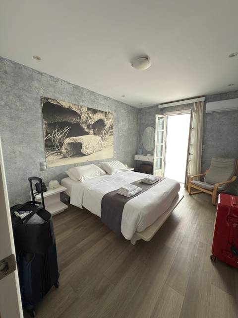 Bright hotel room with double bed and open balcony.