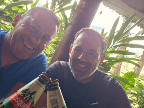 Two men sharing a drink with smiles.