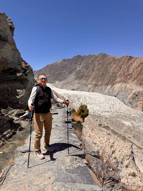 Man hiking along a ledge near a glacier.